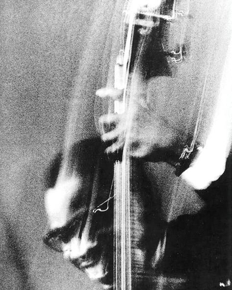 black and white photograph of a man playing an electric guitar with blurry image in the background