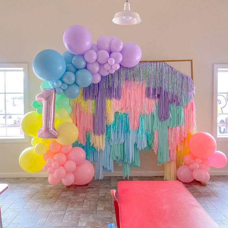 a room filled with balloons and streamers on the wall next to a bench in front of a window