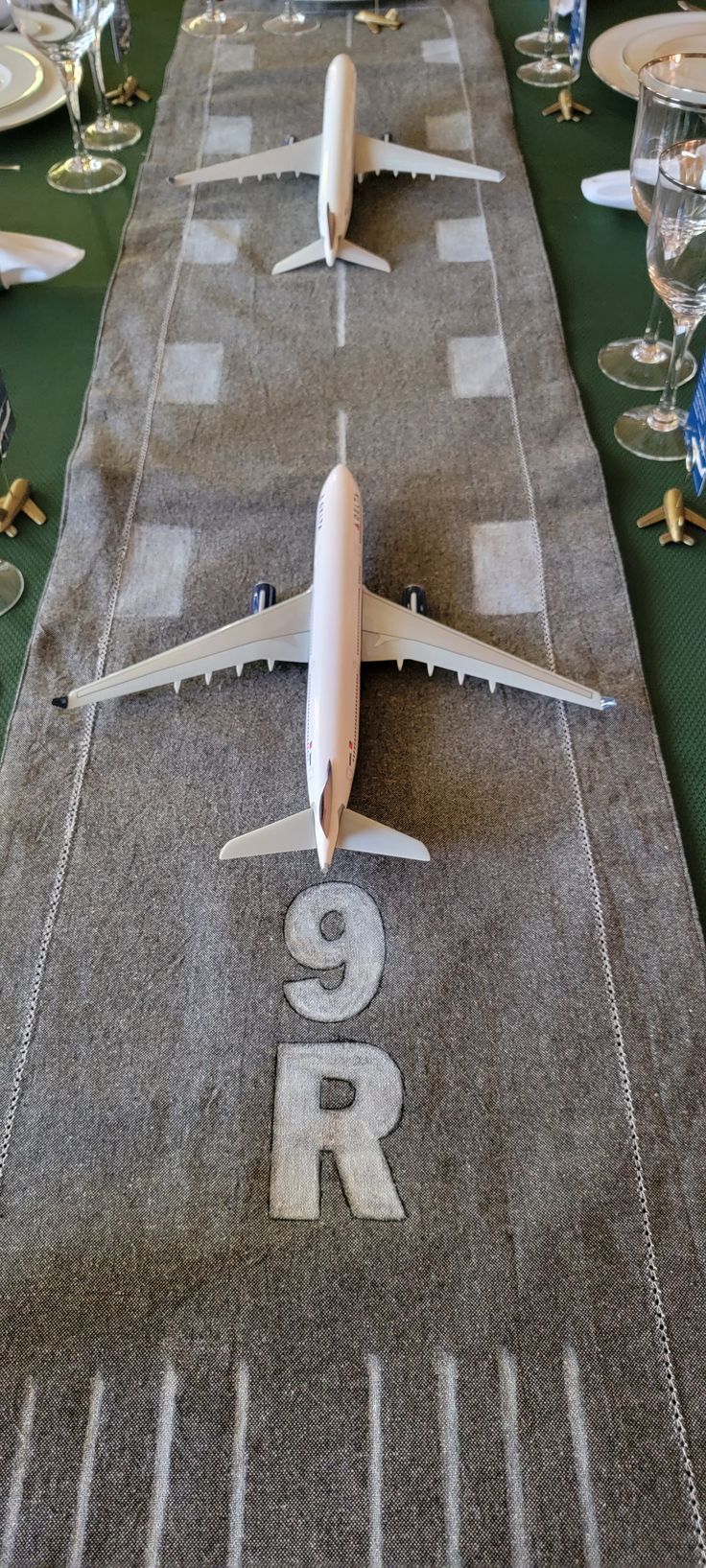 an airplane is on top of a table with wine glasses and silverware around it