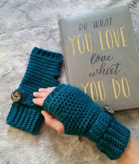 a person is holding two green knitted mittens next to a book that says do what you love about you do