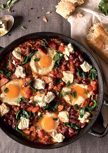 an iron skillet with eggs, spinach and other food items on the table