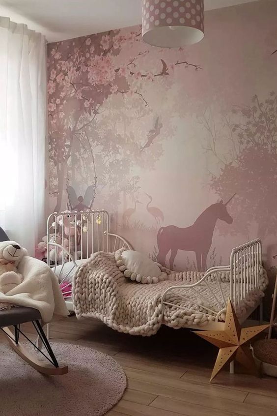 a child's bedroom decorated in pink and white with deer wallpaper, rocking chair, crib and bed