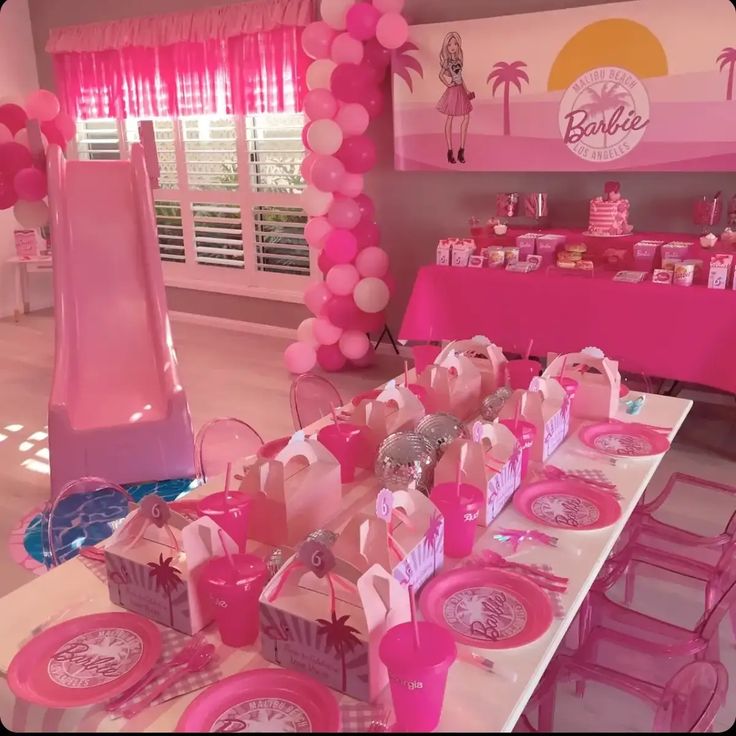 a table set up with pink and white plates, napkins, and candy bars