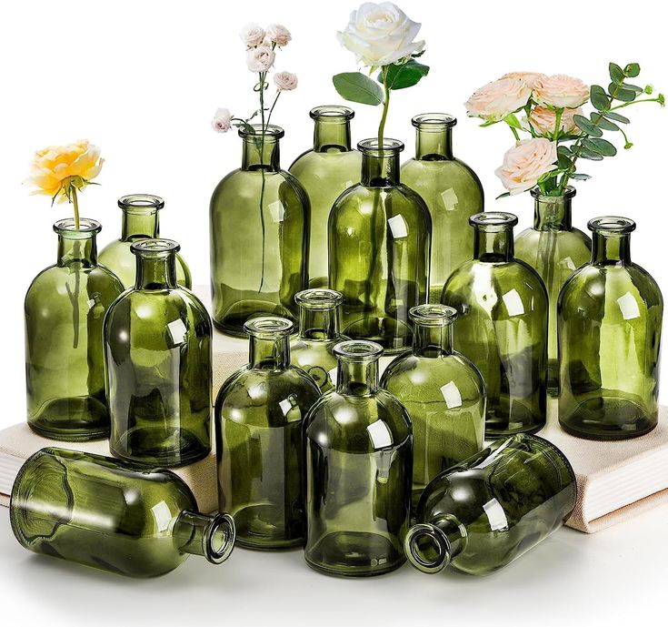 a bunch of green glass bottles with flowers in them