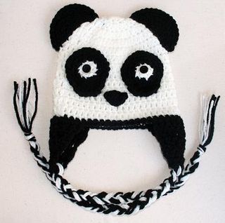 a crocheted panda bear hat on top of a black and white striped rope