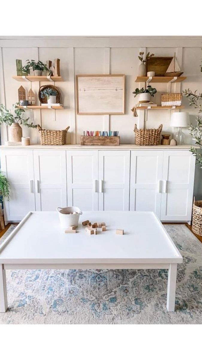 a white coffee table sitting on top of a rug in front of a wall filled with shelves