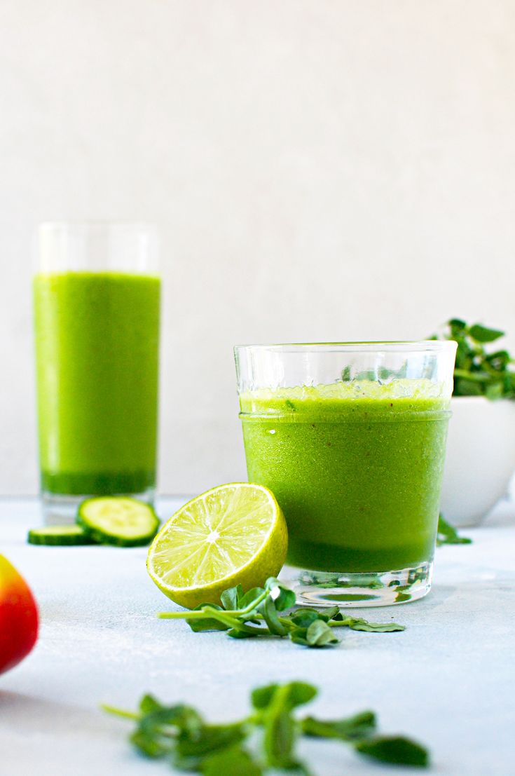 three glasses filled with green smoothie on top of a white counter next to each other