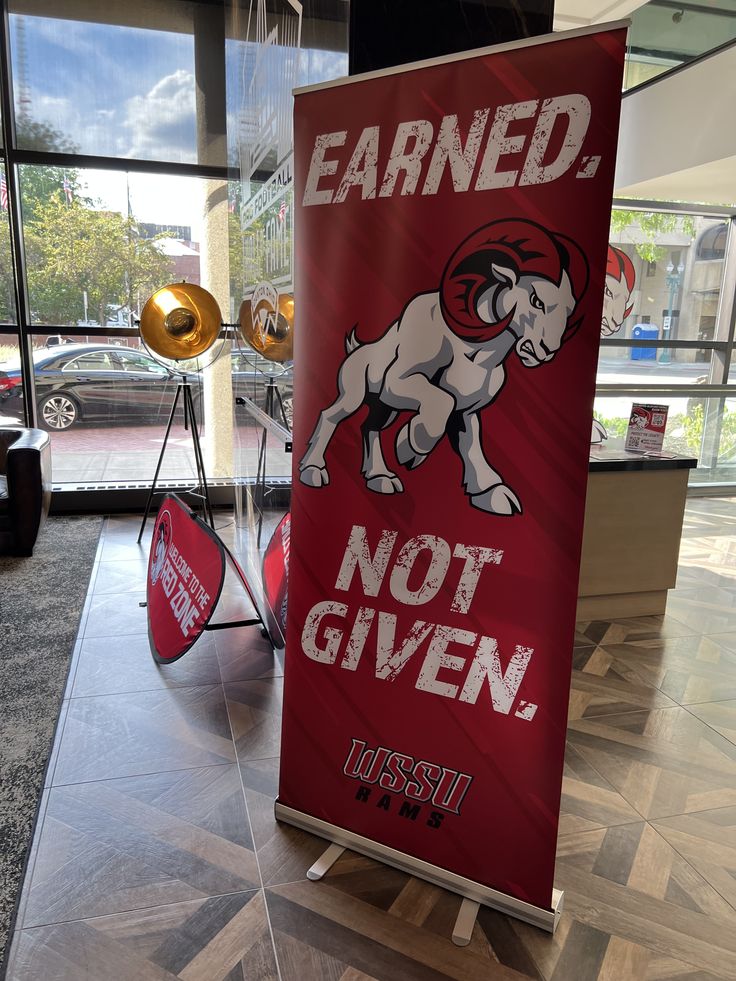 a red sign that says earn and not given in front of a building with large windows