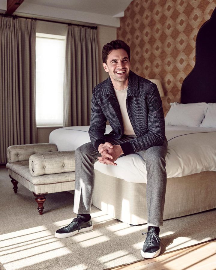 a man sitting on top of a bed in a bedroom next to a large window