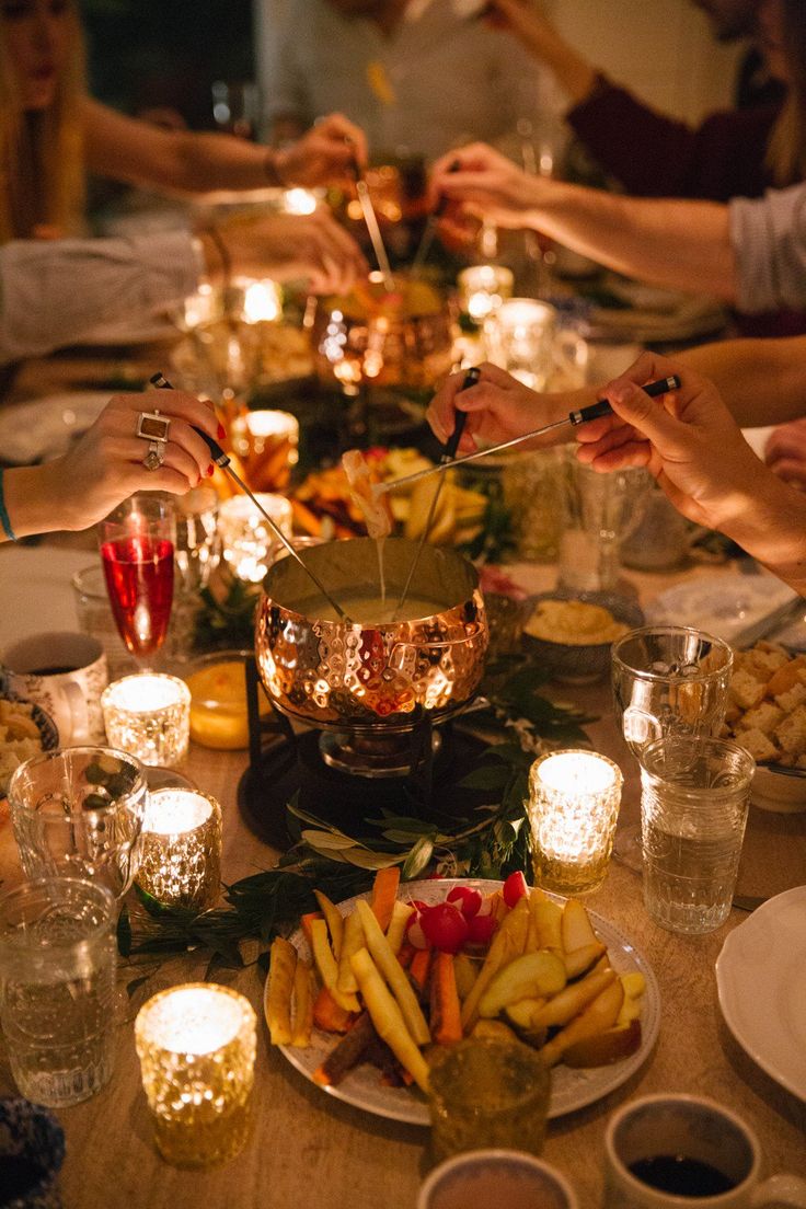 people are sitting at a table with food and candles