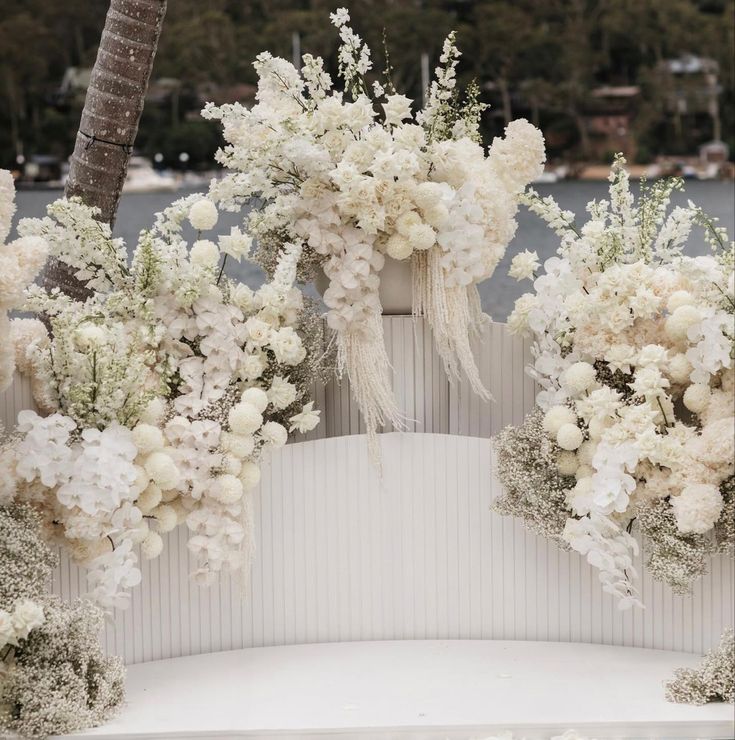 an outdoor ceremony with white flowers and greenery on the ground, along with palm trees