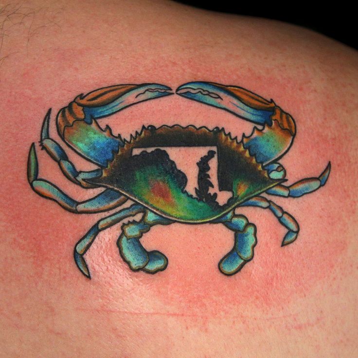 a colorful crab tattoo on the back of a man's shoulder