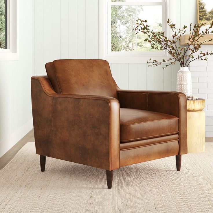 a brown leather chair sitting on top of a rug in front of a white fireplace