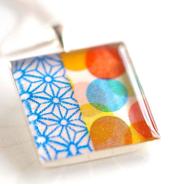 a small square pendant with colorful circles on it