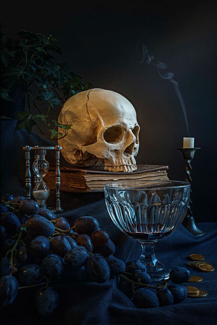 a skull sitting on top of a table next to a glass bowl filled with liquid