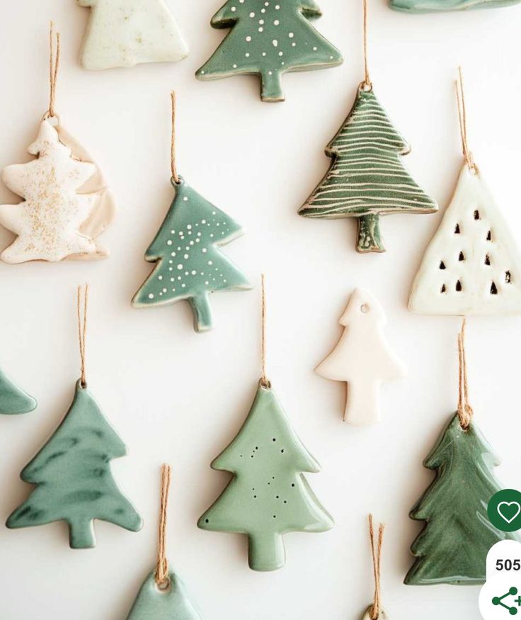 christmas tree ornaments are hanging from strings on a white wall with green and white decorations