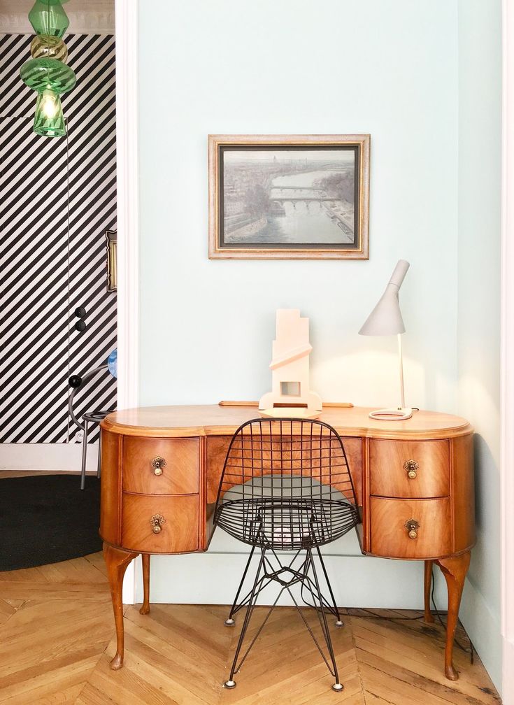 a desk with a chair next to it and a painting on the wall behind it