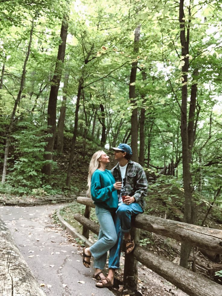 a man and woman standing on a bridge in the woods