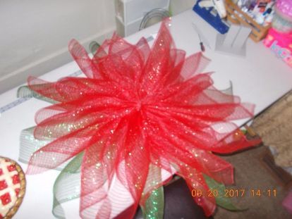 a large red flower sitting on top of a desk