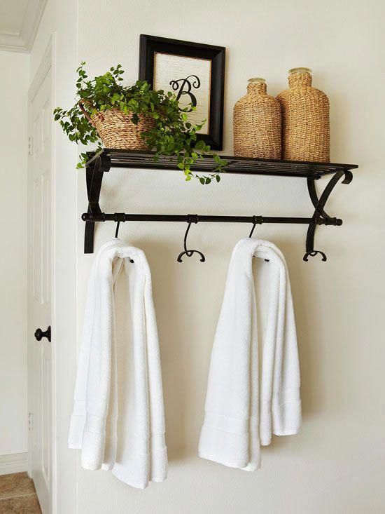 two towels hanging on a rack next to a potted plant and framed photograph in the background