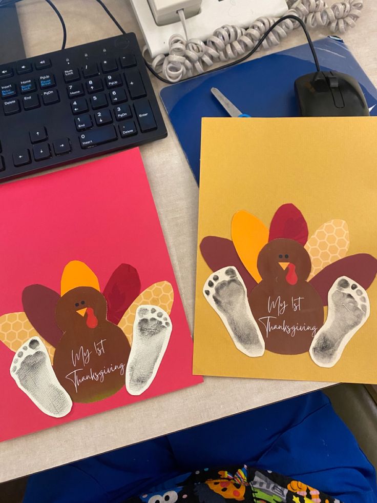 two cards with turkeys and feet on them sitting next to a computer keyboard,