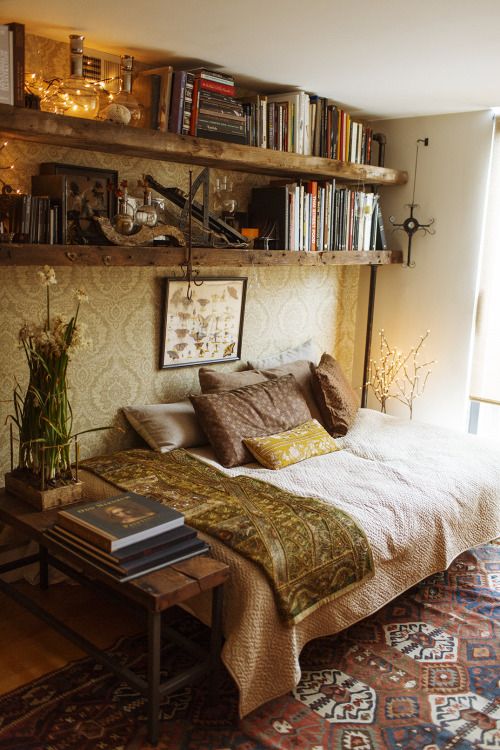 a bed sitting in a bedroom next to a book shelf filled with lots of books