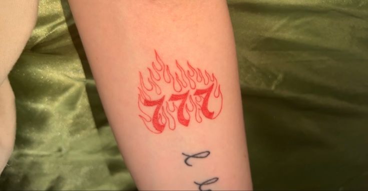 a woman with a tattoo on her arm that has the number seventy seven in it