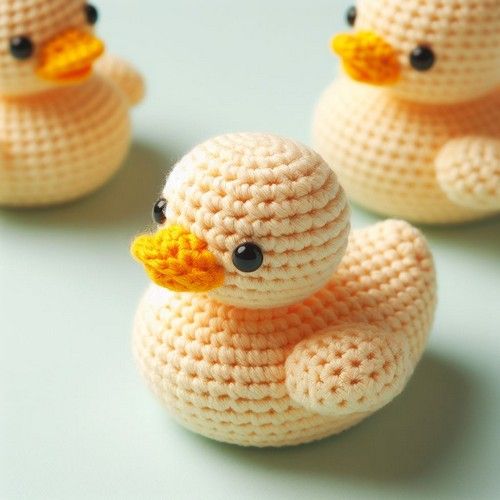 three crocheted ducks sitting next to each other on a blue surface with black eyes