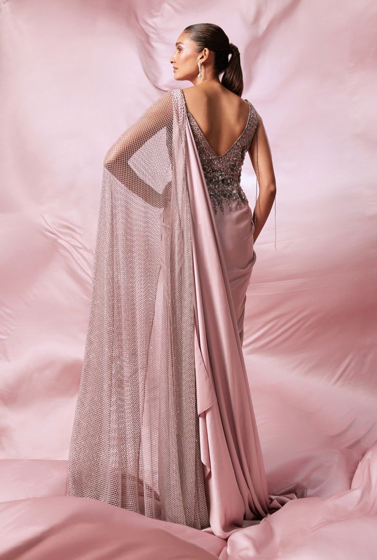 Elegance meets craftsmanship in our soft pink double palla saree gown. This exquisite piece showcases a sophisticated draping technique, beautifully hand-embroidered with sequins, katdana, and shimmering crystals. Evening Draped Gown With Zari Work, Embellished Saree Dress For Gala, Elegant Saree Dress For Gala, Festive Embellished Pre-draped Saree For Gala, Festive Saree For Gala, Anarkali Pre-draped Saree With Sequins For Evening, Pink Saree With Mirror Work, Elegant Draped Pink Lehenga, Evening Gown With Resham Embroidery In Traditional Drape