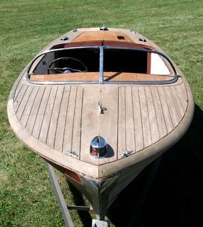 a wooden boat sitting on top of a lush green field next to a grass covered field