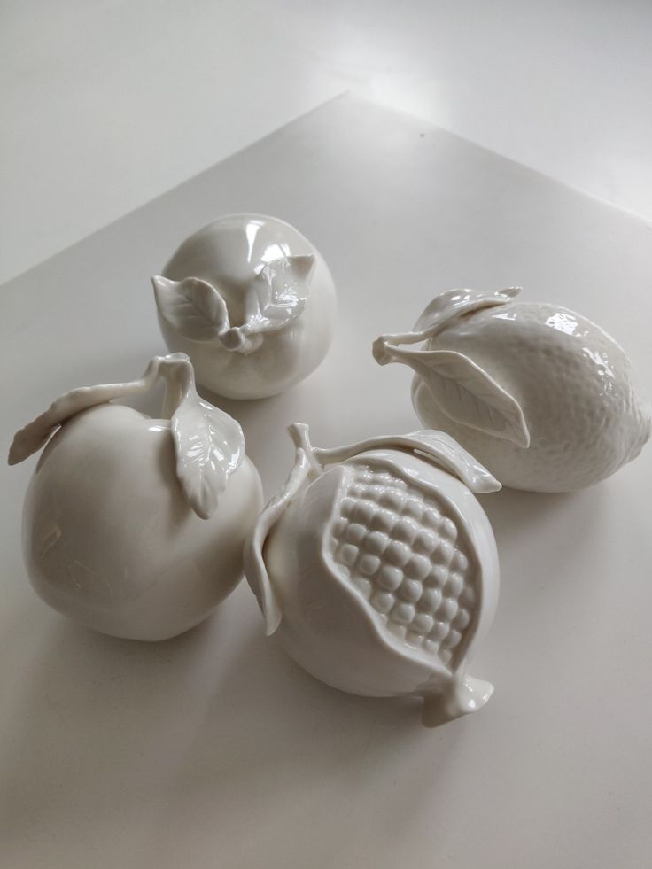 three white vases sitting on top of a table next to an apple and two other items