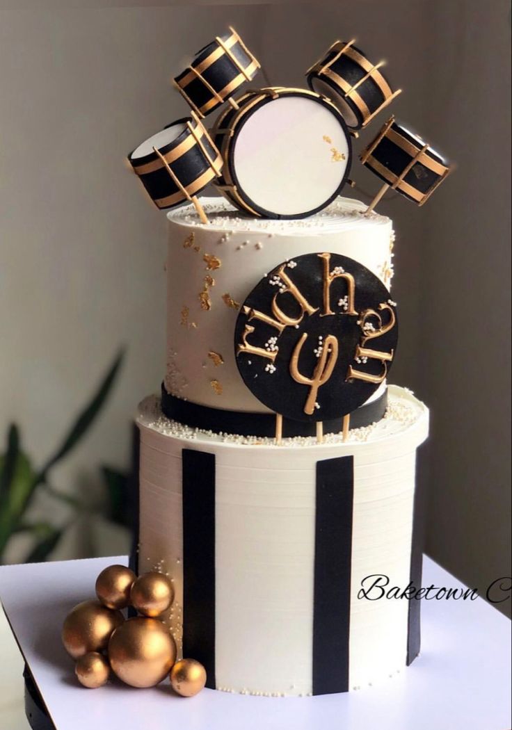 a three tiered cake decorated with black and white stripes, gold decorations and a clock on top