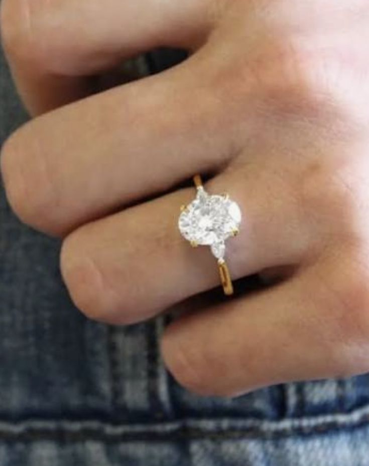 a person's hand wearing a ring with a flower on it and a diamond in the middle