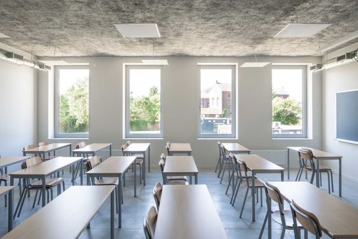 an empty classroom with wooden desks and windows