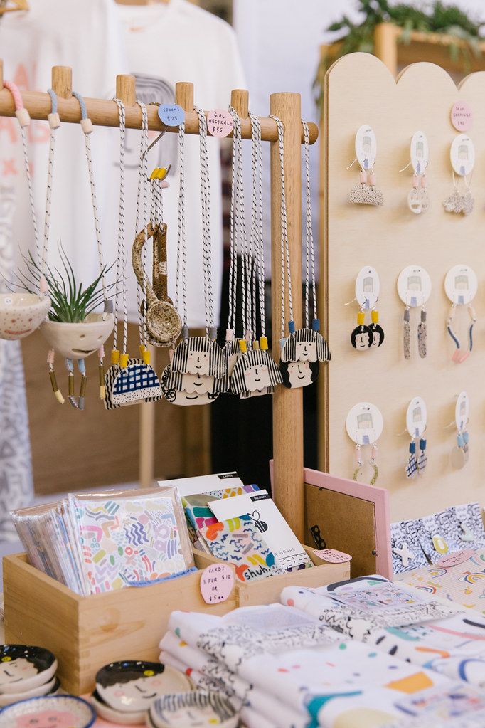 an assortment of jewelry on display at a craft fair or sale with other items in the background