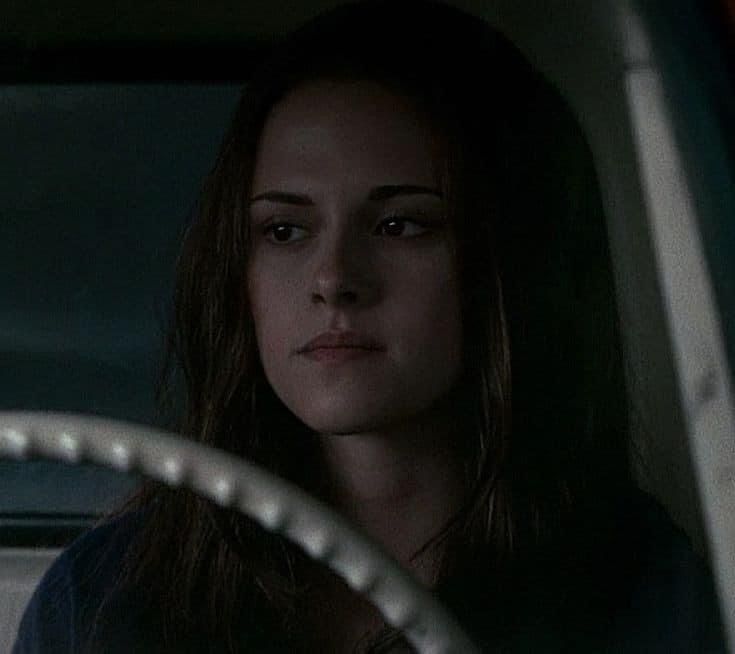 a woman sitting in the driver's seat of a car with her hand on the steering wheel