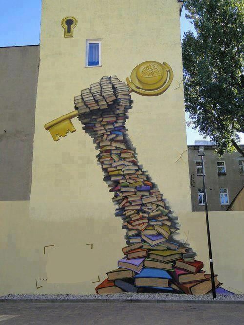 a mural on the side of a building with a key and book stacked up to it