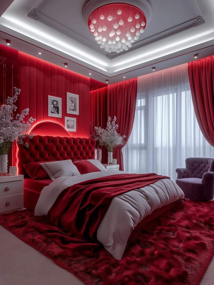 a bedroom decorated in red and white, with a large bed surrounded by velvet curtains