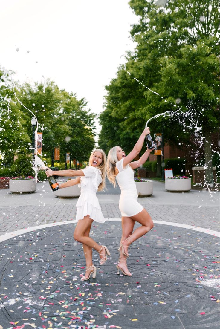 two women in white dresses are throwing confetti