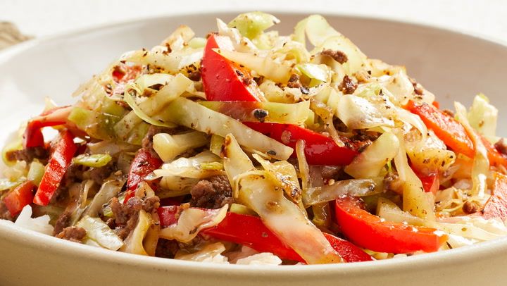 a white bowl filled with cabbage and red peppers