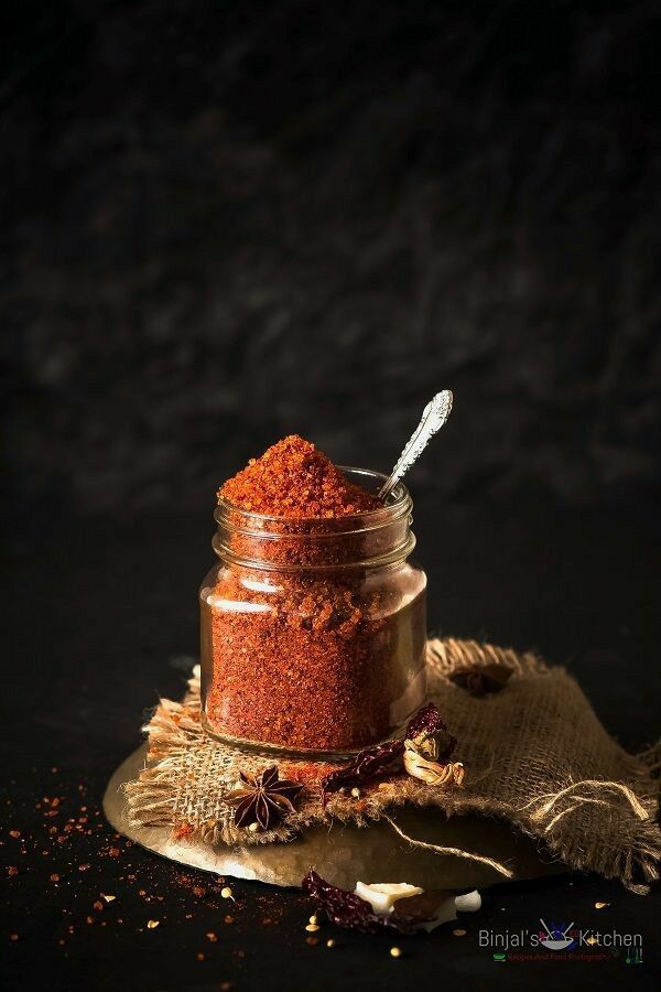 a jar filled with spices sitting on top of a table next to a cloth and spoon