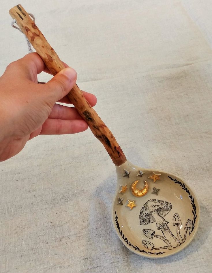 a hand holding a wooden spoon with an animal design on the side and gold accents