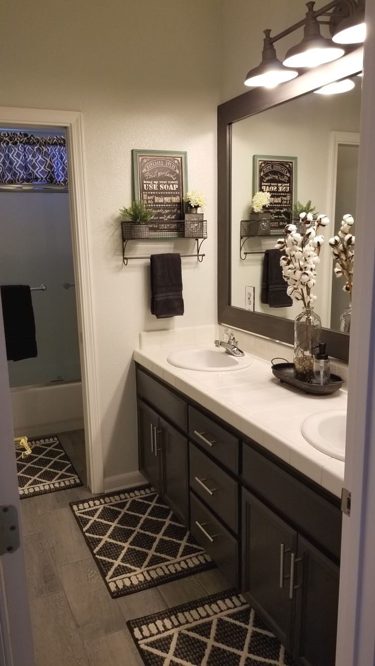 a bathroom with black and white rugs on the floor, two sinks and a large mirror