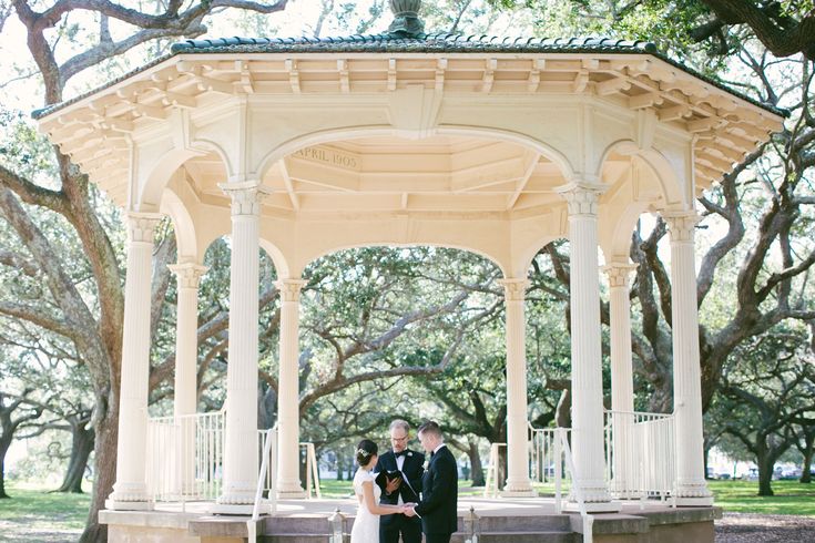 a bride and groom standing in front of a gazebo