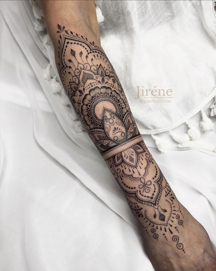 a woman's arm with an intricate tattoo on her left forearm and the wrist