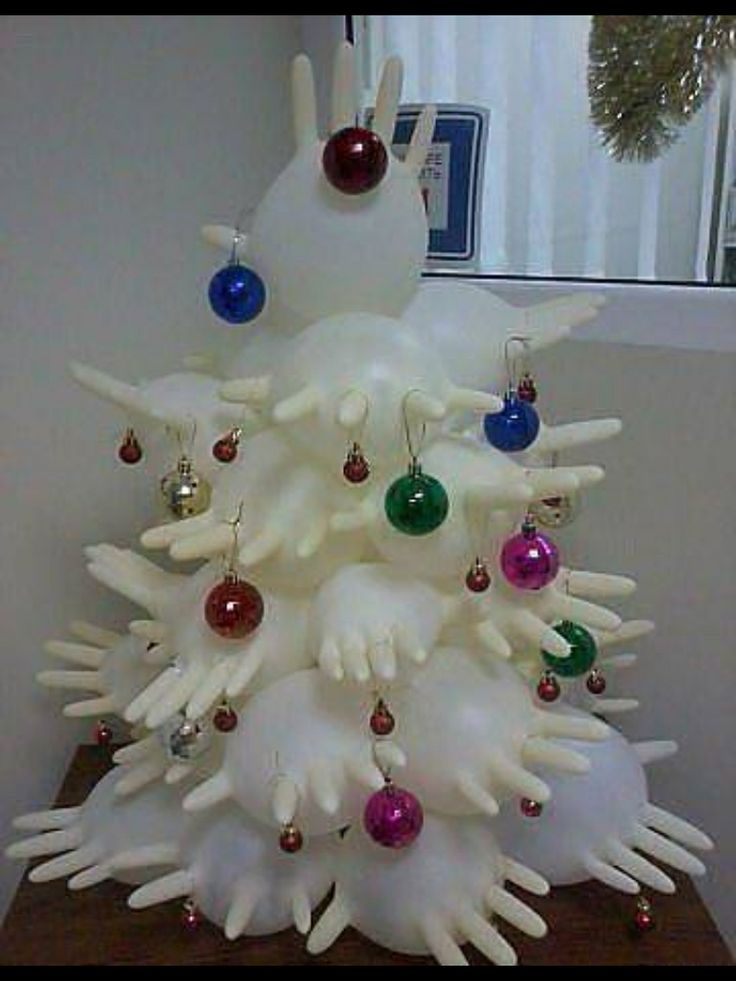 a white christmas tree with ornaments on it's branches and hands sticking out of the top