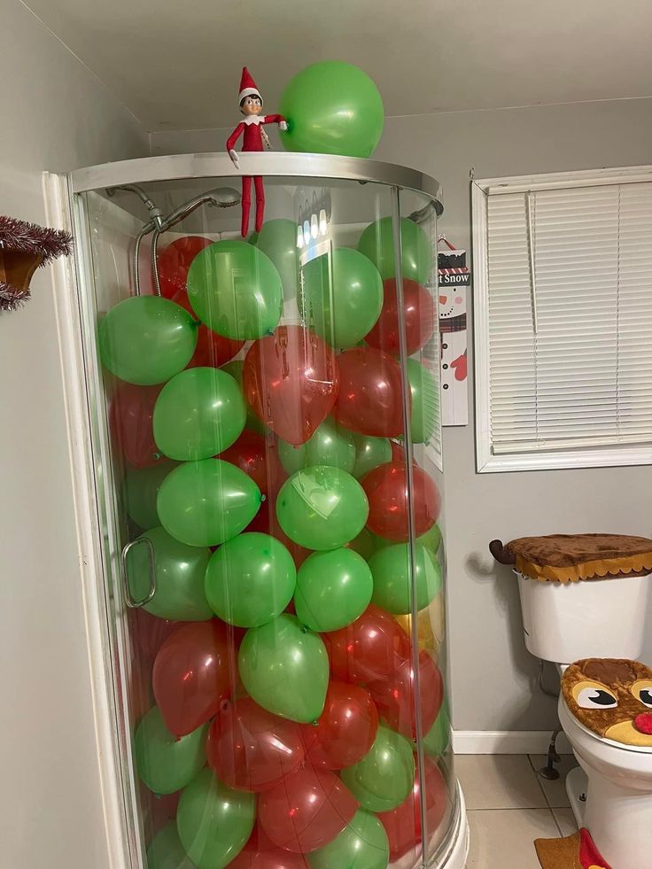 a room filled with lots of green and red balloons next to a trash can on the floor