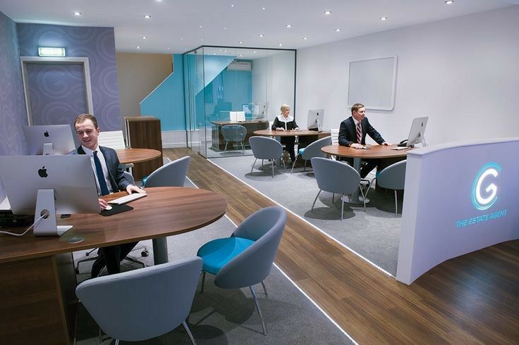 two men sitting at desks in an office setting with computers on each side of them