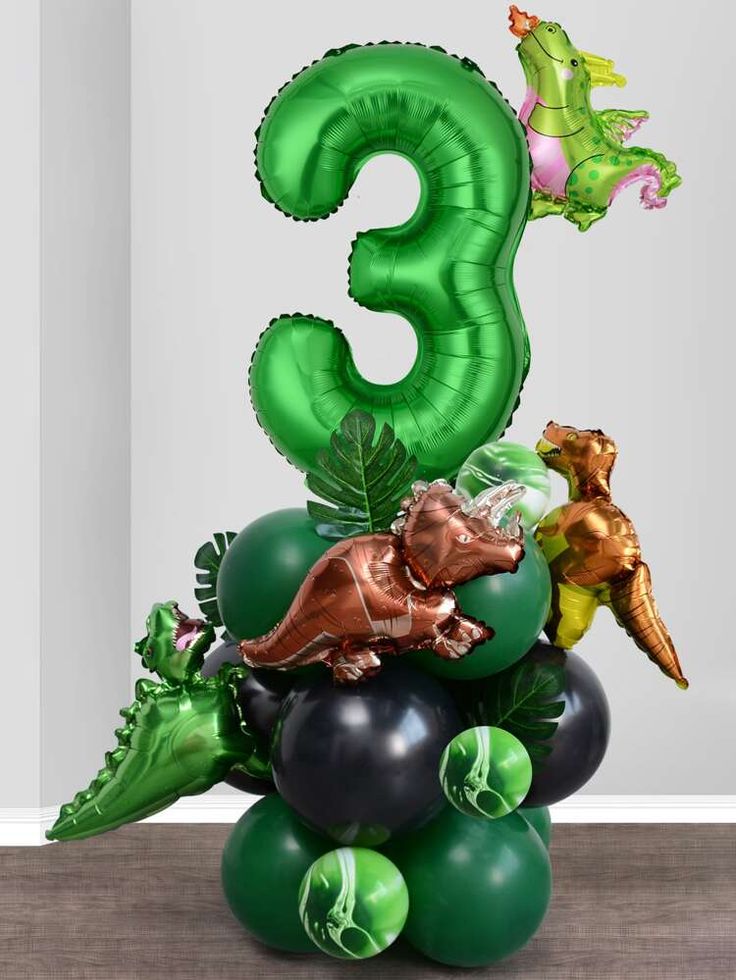 the number three is made out of balloons with dinosaurs on it and other decorations around it