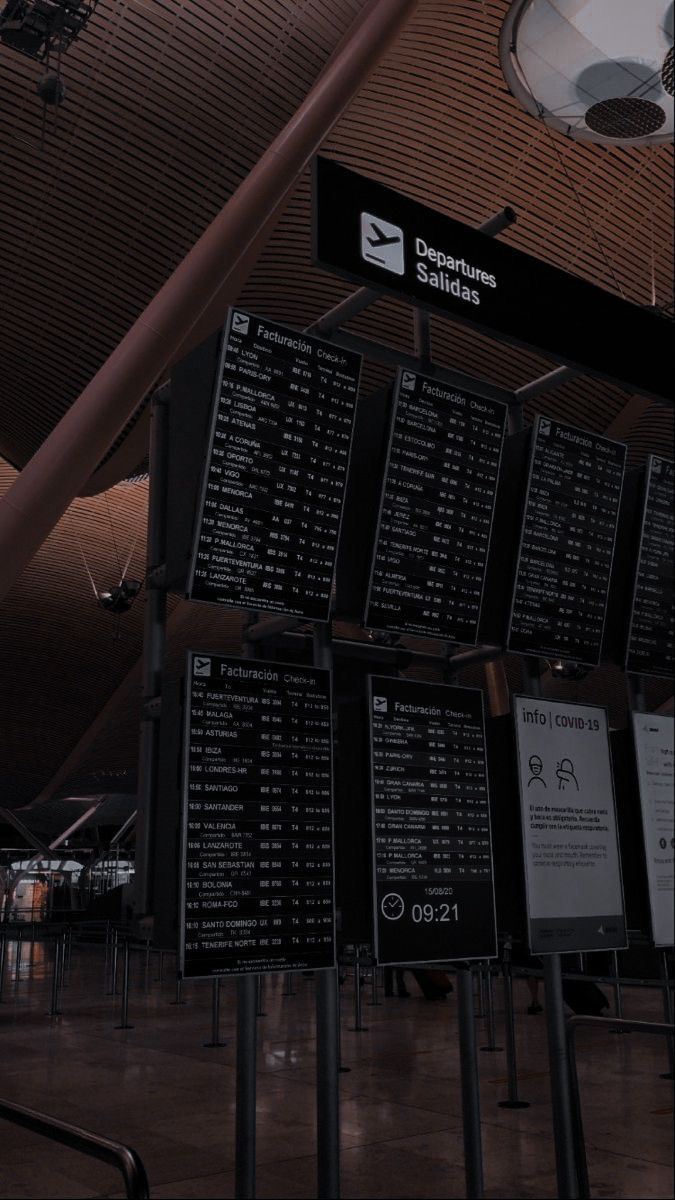 black and white photo of an airport terminal with many signs on the wall above it